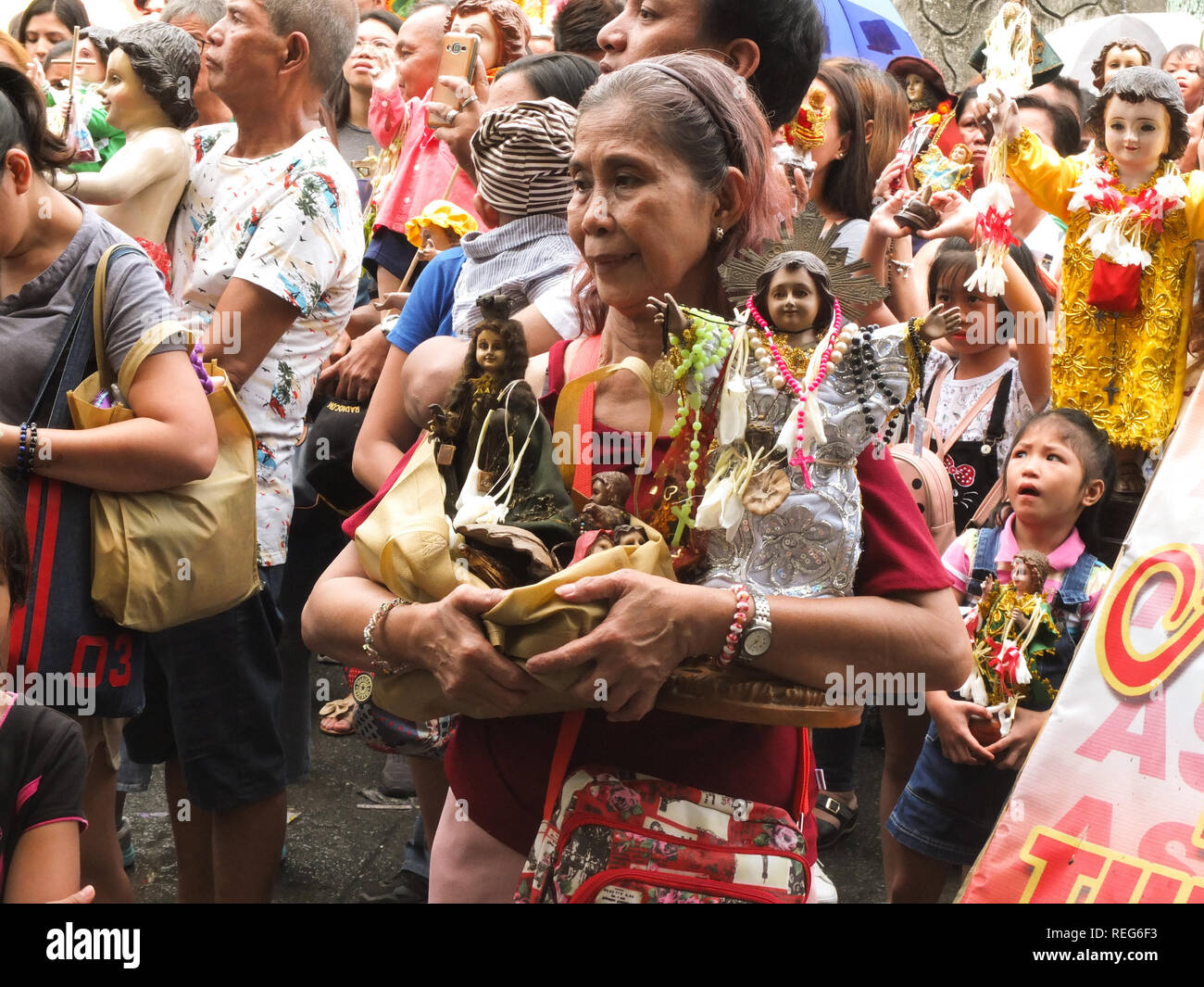 An old woman carrying her Sto. Niños during the Feast of the Sto. Niños in Tondo. Catholic Devotees bring their Sto. Niños to be blessed by holy water by the parish priest of Tondo church to celebrate the Feast of the Santo Niño (Child Jesus). Stock Photo