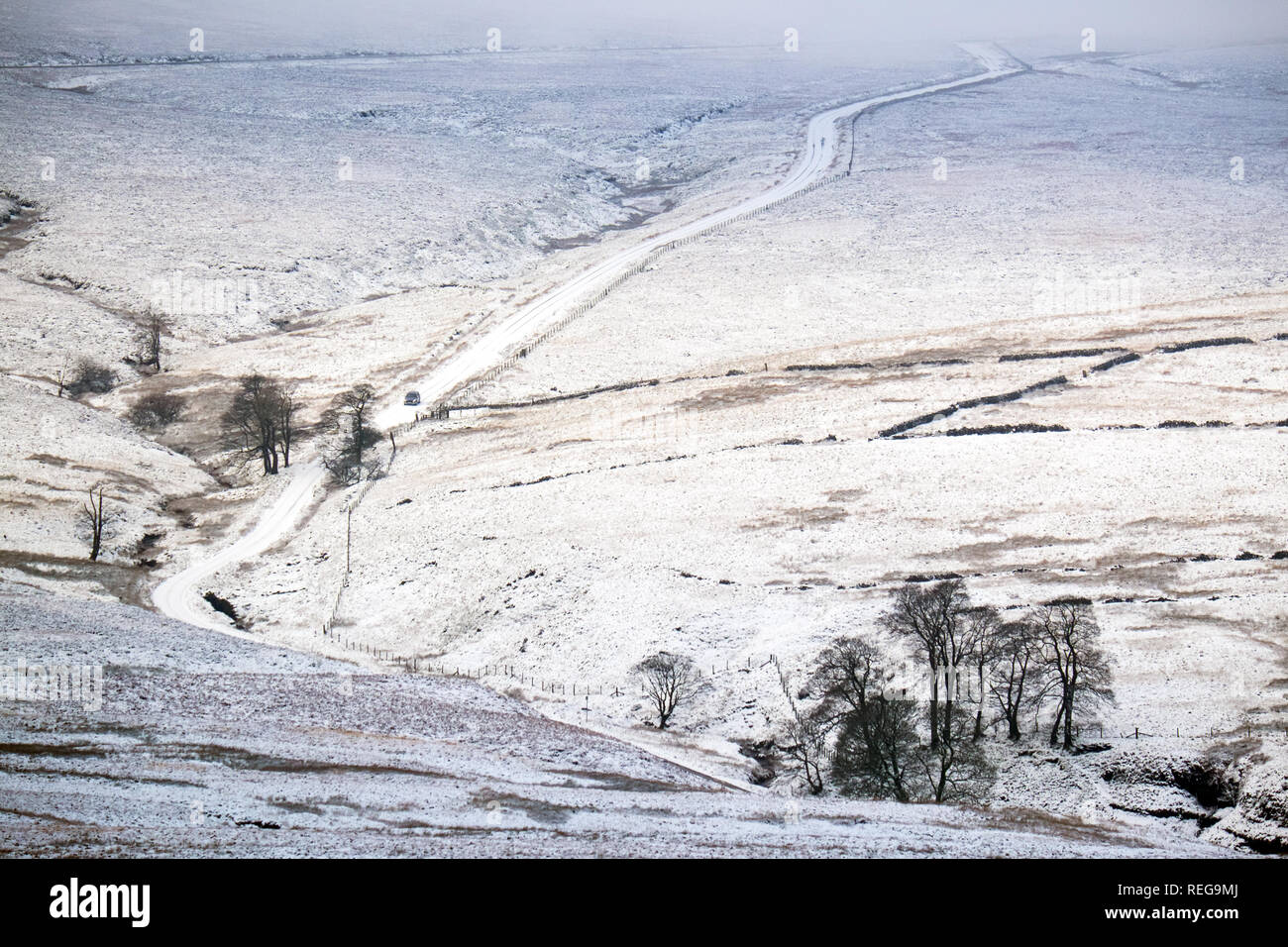 Narrow single track country road covered in snow on the moors of the Peak District just outside the town of Buxton Stock Photo