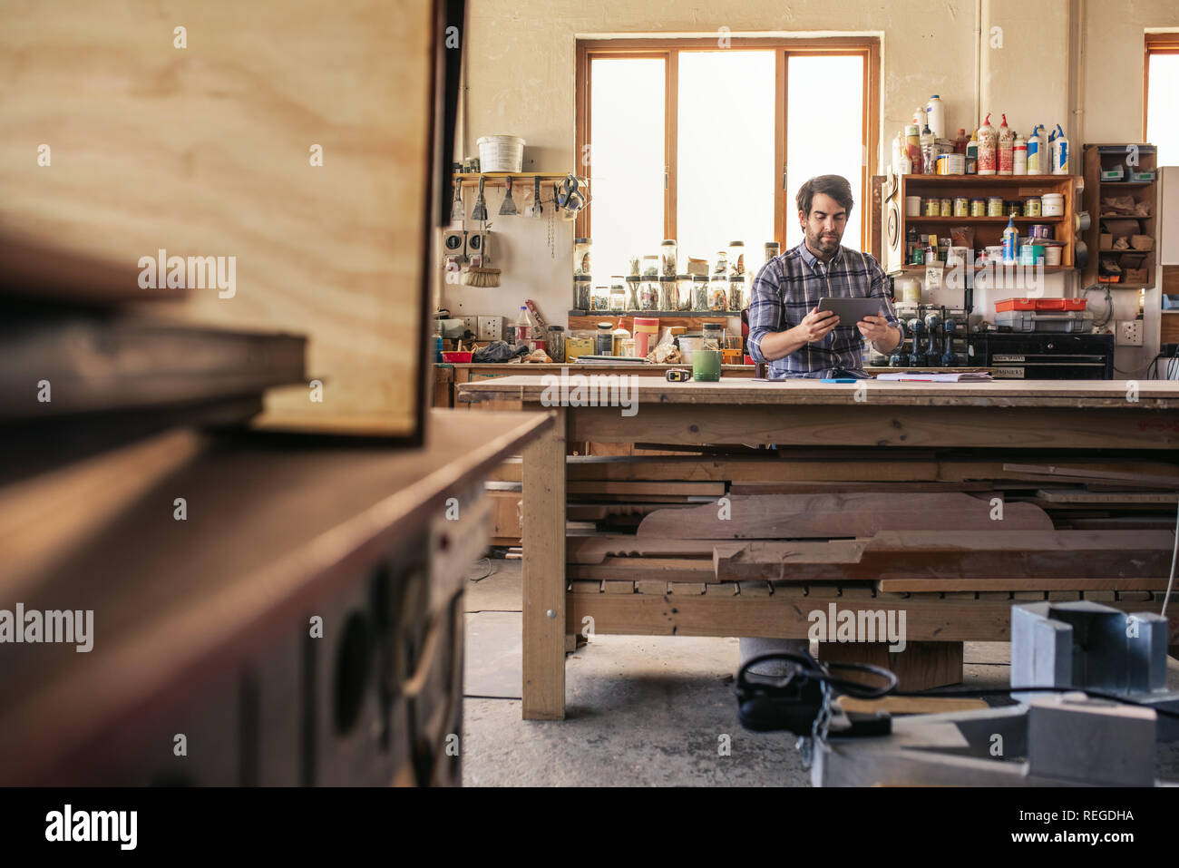 Woodworker using a tablet while sitting at his workbench Stock Photo