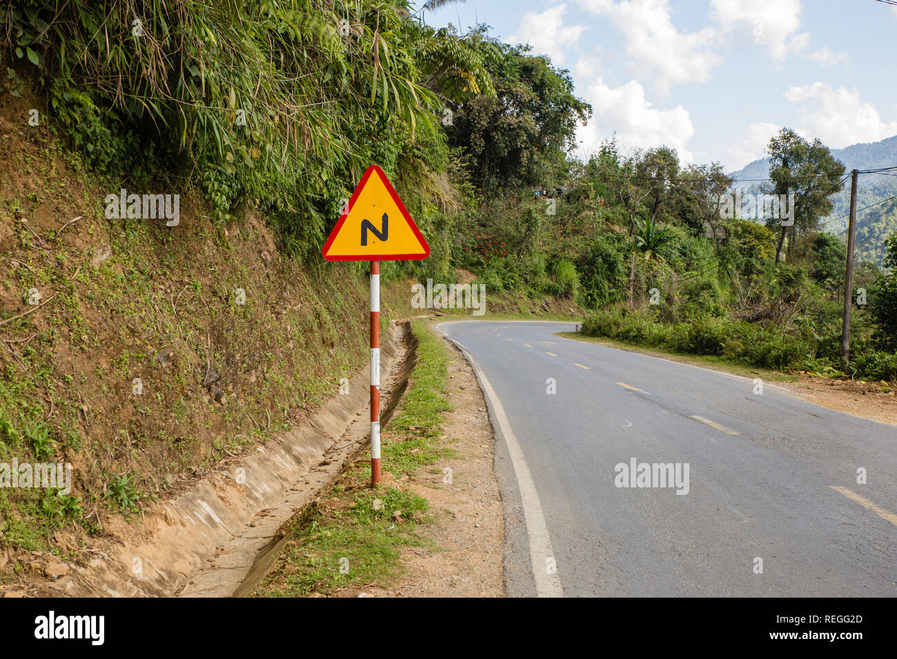 sign winding road on a mountain road, warning traffic sign Vietnam Stock Photo