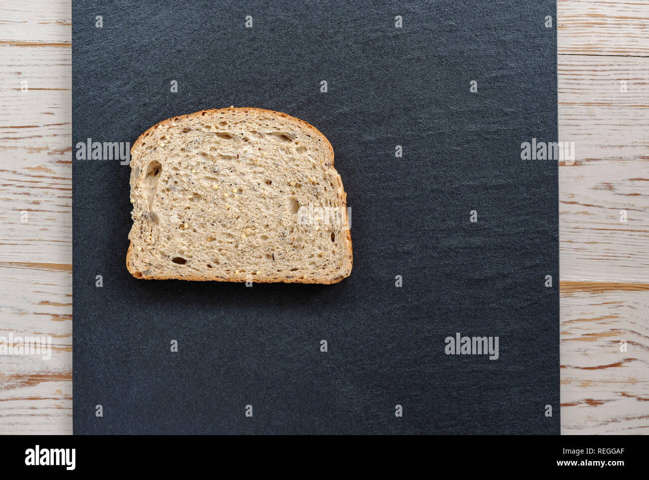 Slice of seeded batch bread on a piece of slate. Stock Photo