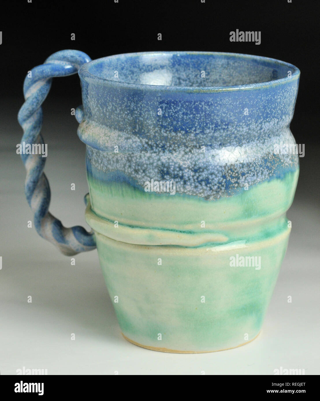 Broken blue and jade wheel thrown mug with twisted rope handle Stock Photo