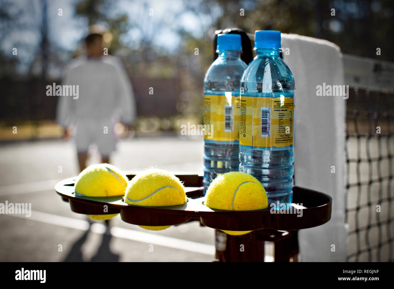 Holder on the side of a tennis court net with spare balls and water