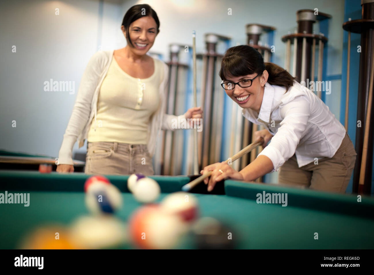 Two young woman playing a friendly game of pool. Stock Photo
