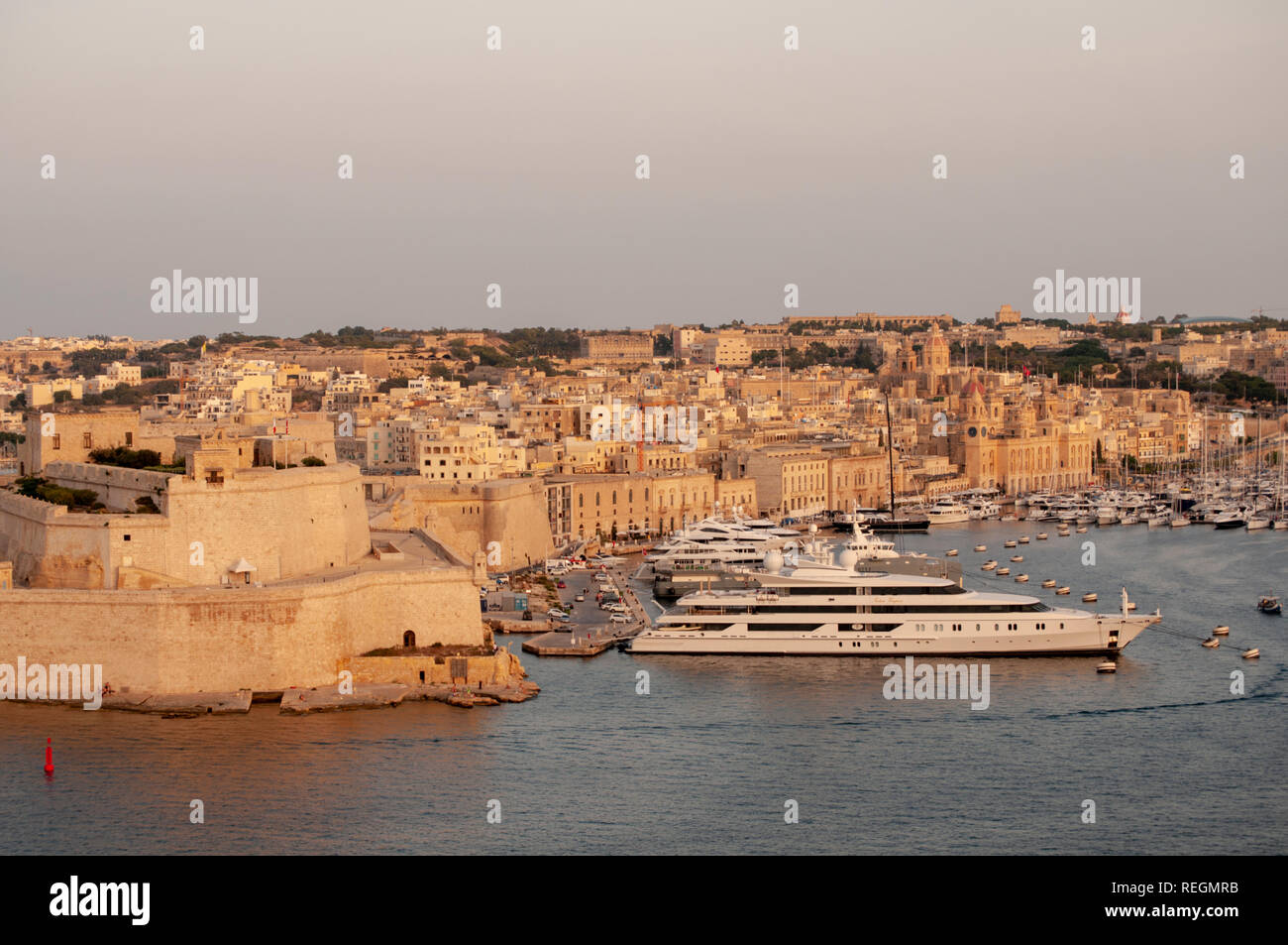 View from Upper Barrakka Gardens in Valletta, Malta, over the Grand Harbour and Fort St. Angelo with Vittoriosa Yacht Marina in warm evening sunlight. Stock Photo