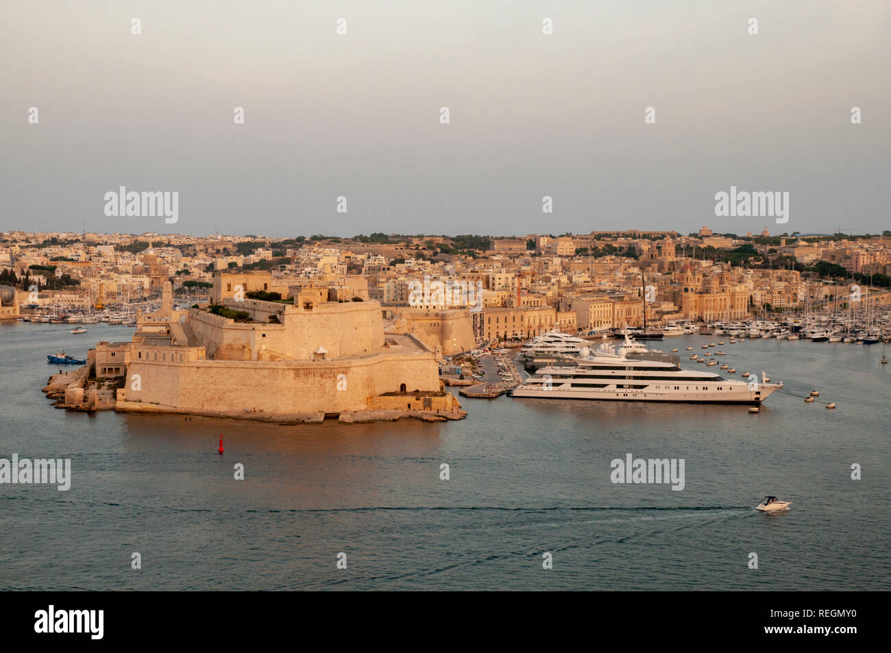 View from Upper Barrakka Gardens in Valletta, Malta, over the Grand Harbour and Fort St. Angelo with Vittoriosa Yacht Marina in warm evening sunlight. Stock Photo