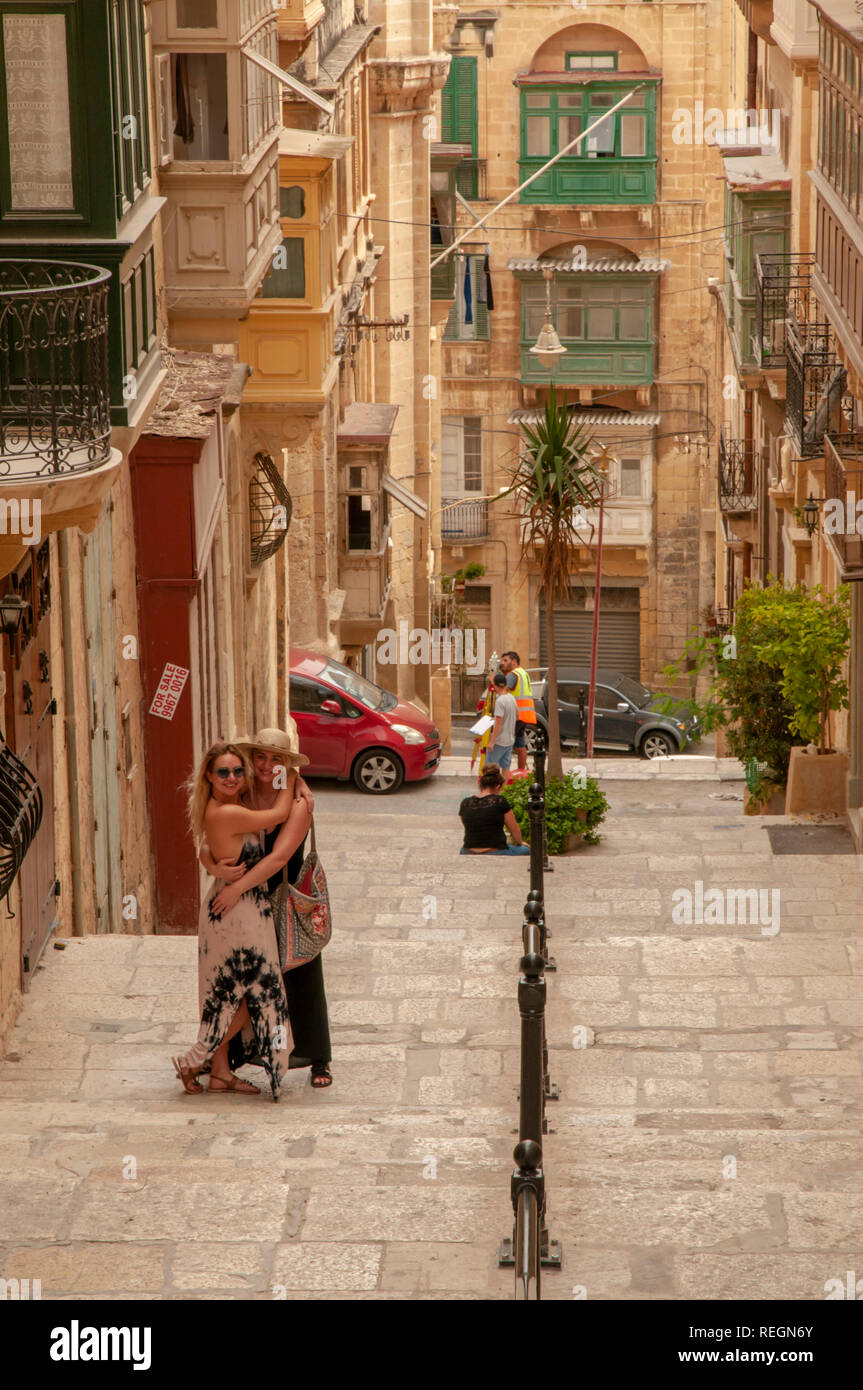 Two ladies embracing on the pedestrian steps of Old Theatre Street in Valletta, the walled capital of Malta. Stock Photo
