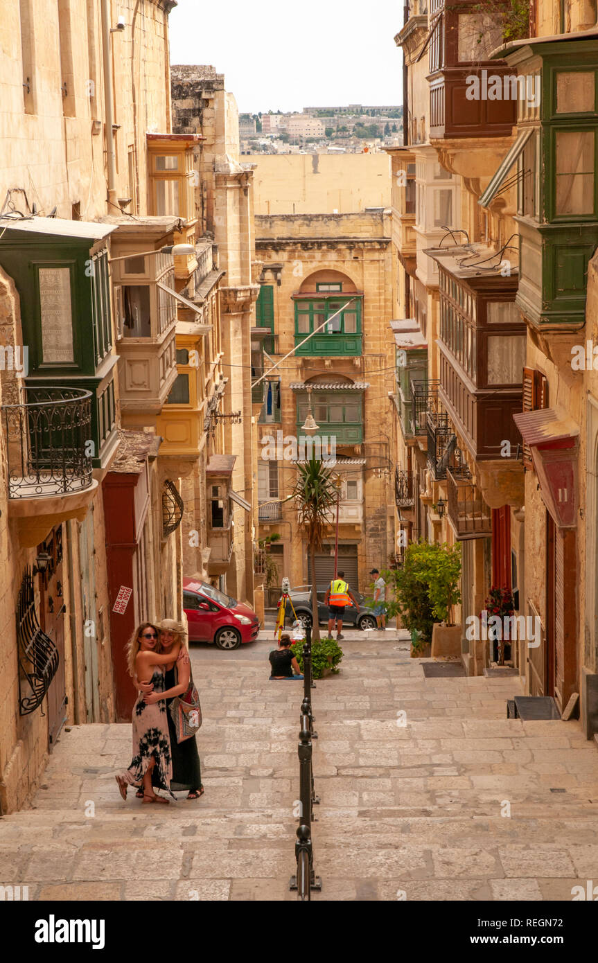 Two ladies embracing on the pedestrian steps of Old Theatre Street in Valletta, the walled capital of Malta. Stock Photo