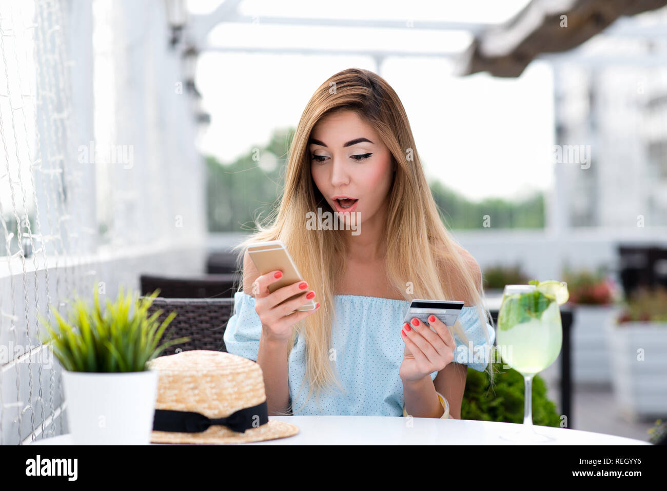 Girl cafe in summer. Pay breakfast and lunch with plastic card by phone via Internet application. Emotion of surprise, shocked valuable product. Concept of misunderstanding confusion big write-off. Stock Photo