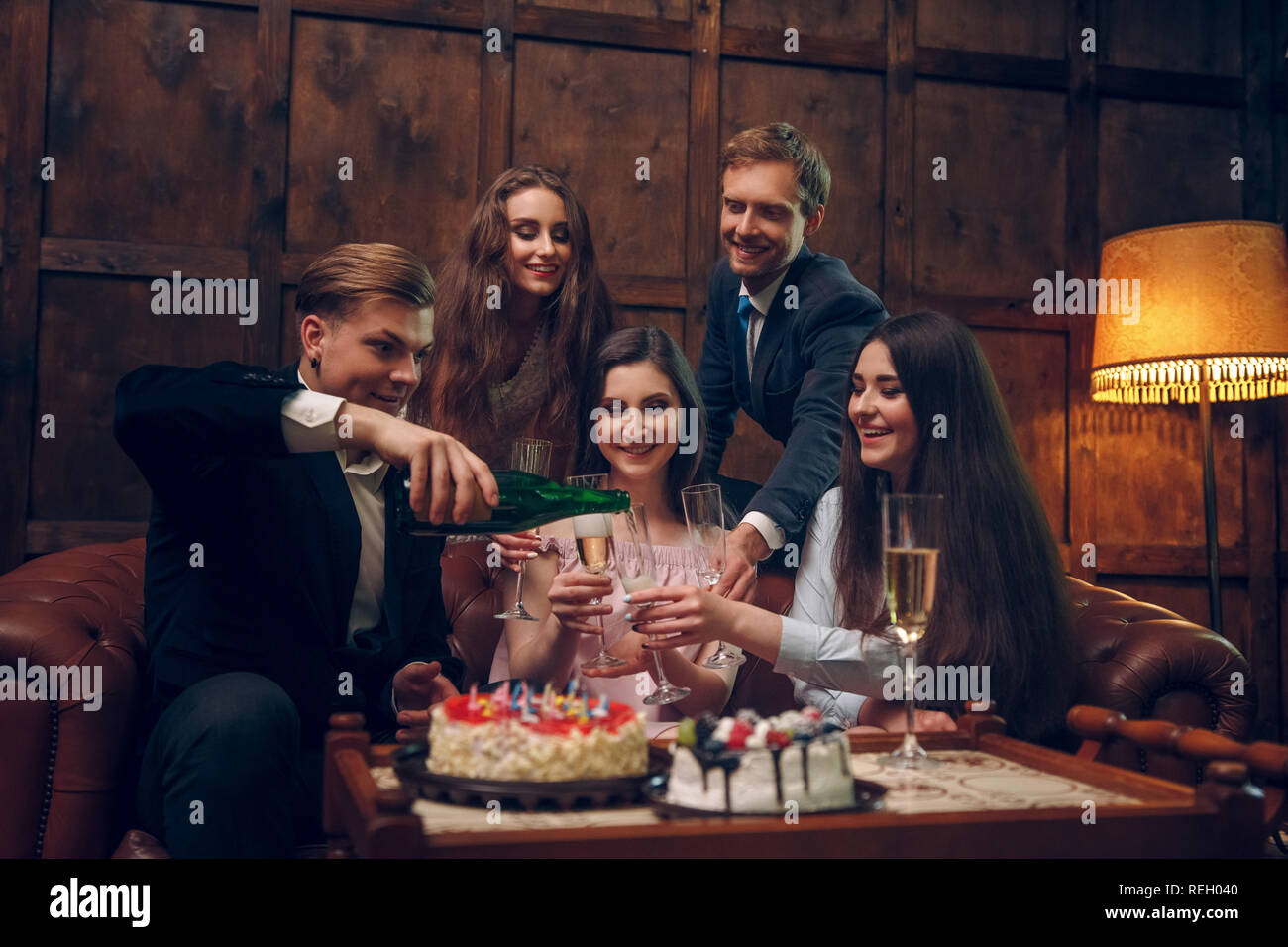 Cheerful friends celebrate birthday by drinking champagne and eating cake Stock Photo