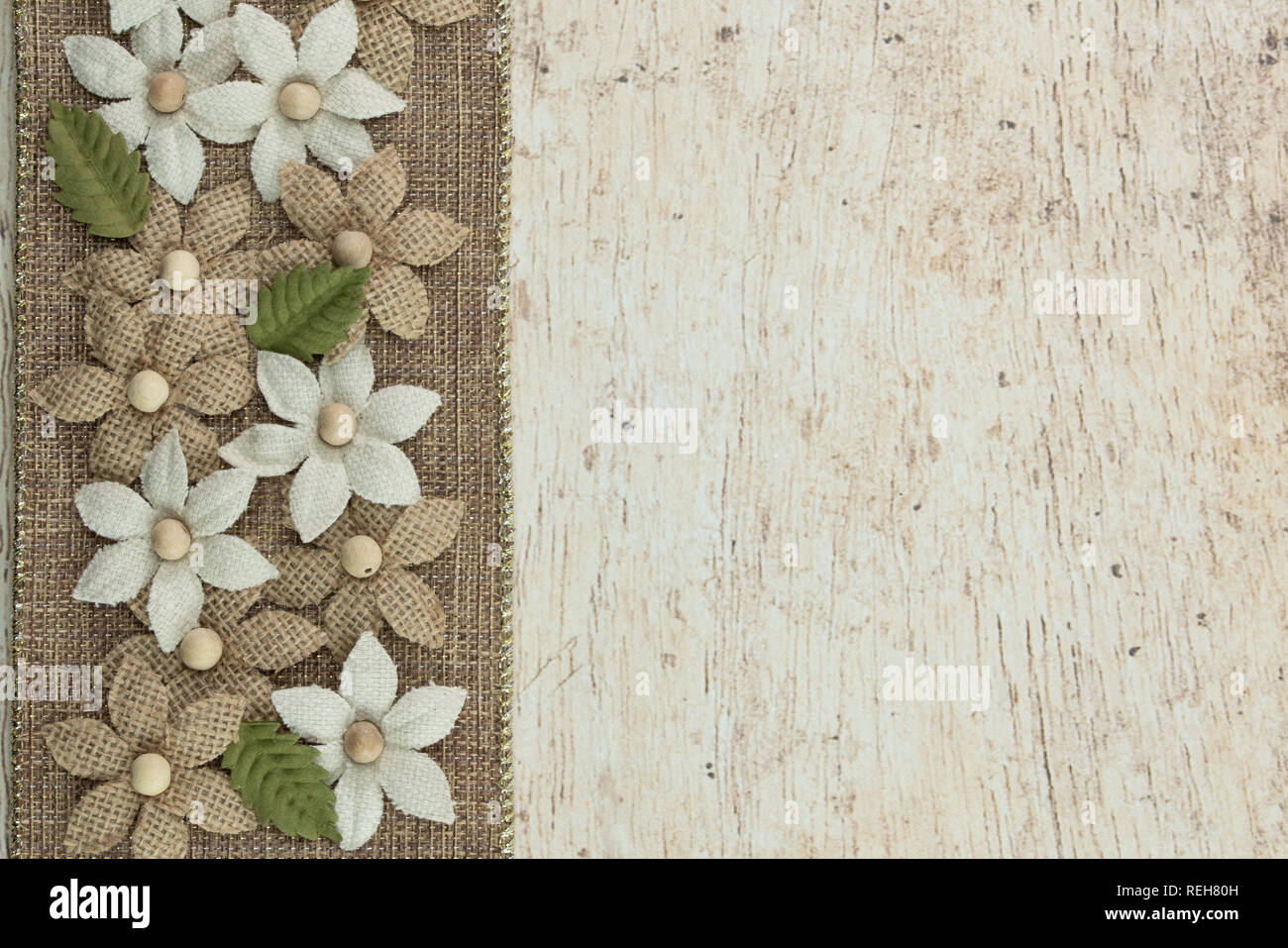 burlap ribbon border with neutral color fabric and bead flowers on a wooden background Stock Photo