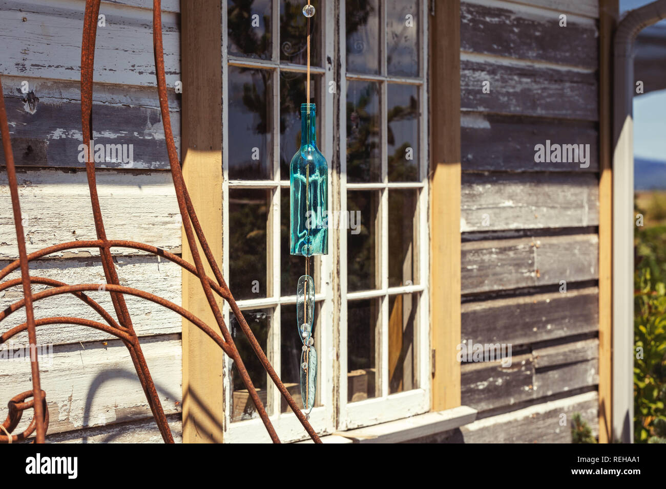 Blue wind chimes garden art made from a glass bottle hanging in front of a window Stock Photo