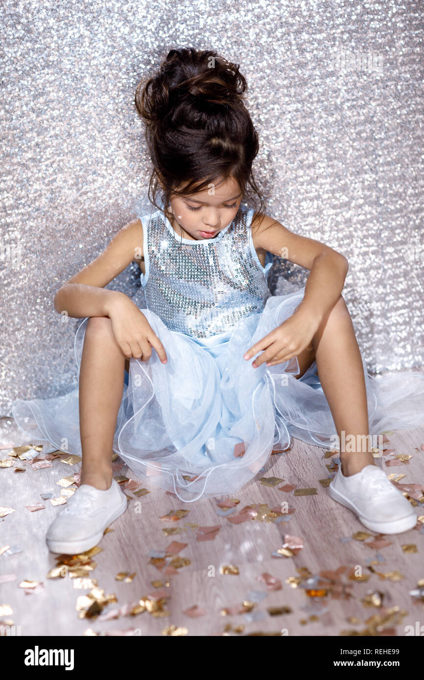 little child girl in dress sitting on the floor with confetti Stock