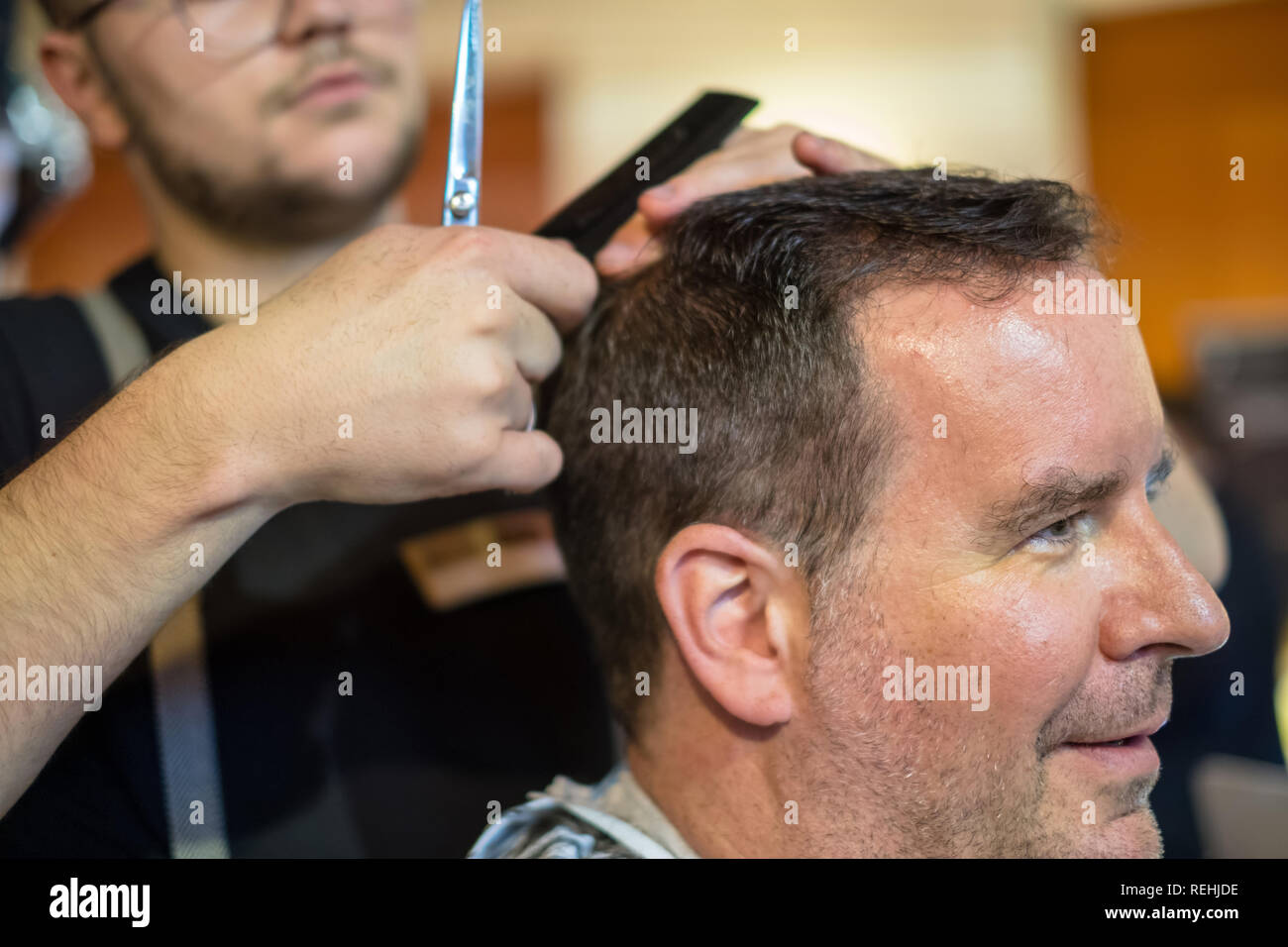 Happy guy getting haircut by hairdresser Stock Photo