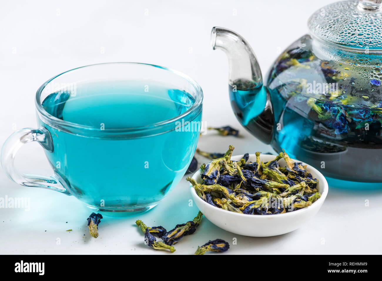 Butterfly pea flower blue tea in a cup with teapot on white marble