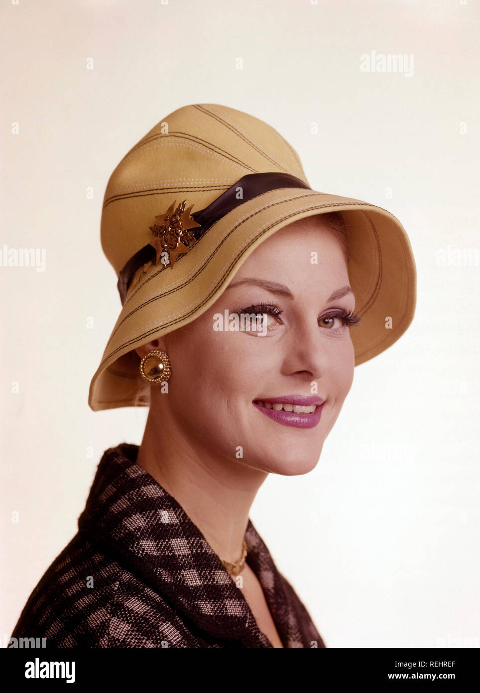 Woman of the 1960s. She is wearing a yellow summer hat. Matching golden necklace, earrings and brooch. Sweden 1960s Stock Photo