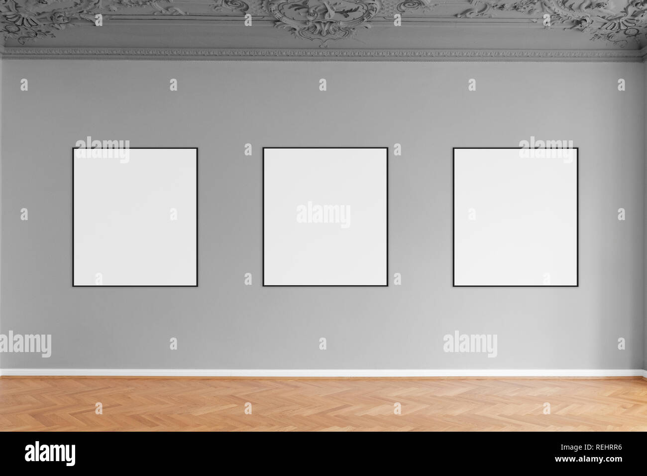 three empty picture frames hanging on grey wall in gallery Stock Photo