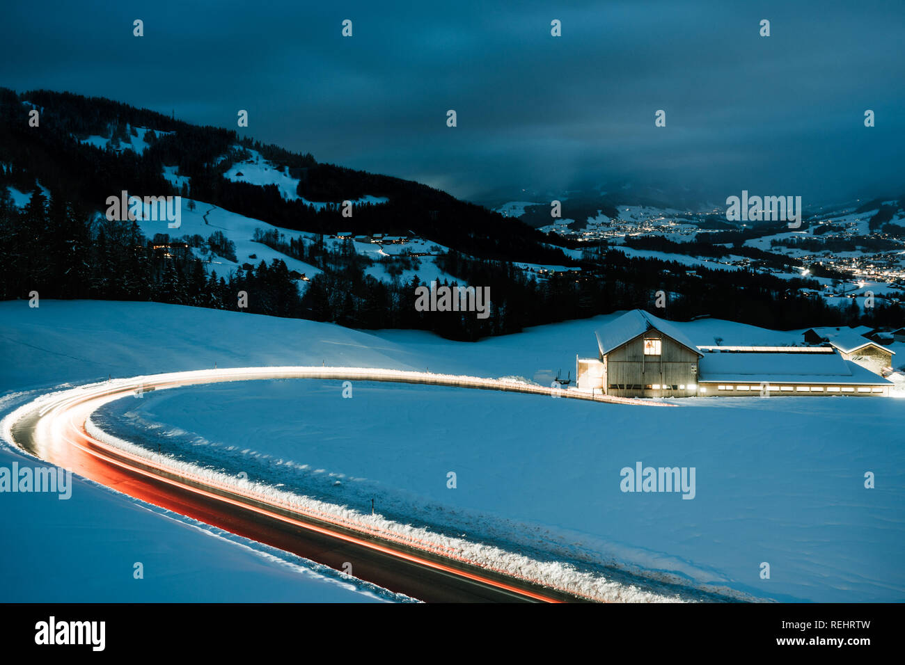 Long exposed night photography of cars driving through a snowy mountain road in the alps of Austria. Stock Photo