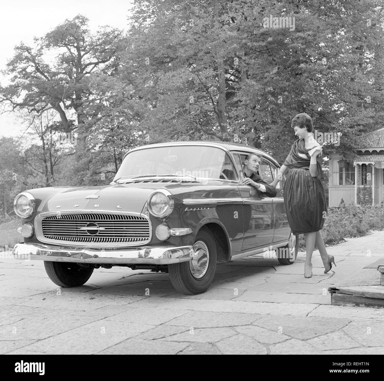 Driving in the 1950s. A young woman is standing beside a car Opel Kapitän, talking to a man behind the wheel. She is fashionable dressed in a typical 1950s dress. Photo Kristoffersson Ref CB93-3 Stock Photo