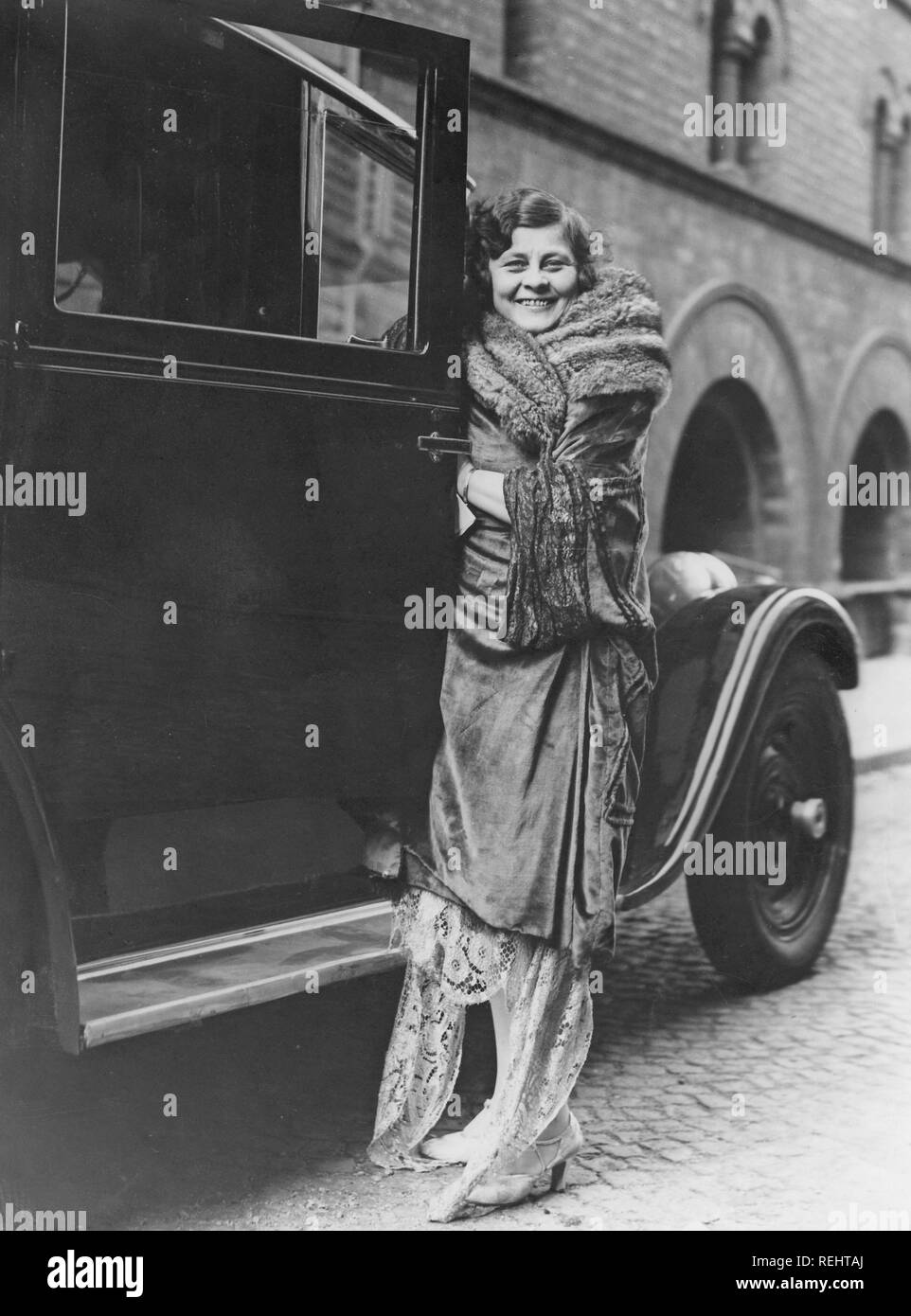 Women's fashion in the 1920s. A young woman in a typical 1920s clothes standing beside a car, opening the door. She is the swedish opera singer Marie Sundelius, 1884-1858. Soprano singer who sang at the Metropolitan in New York with Enrico Caruso. Stock Photo