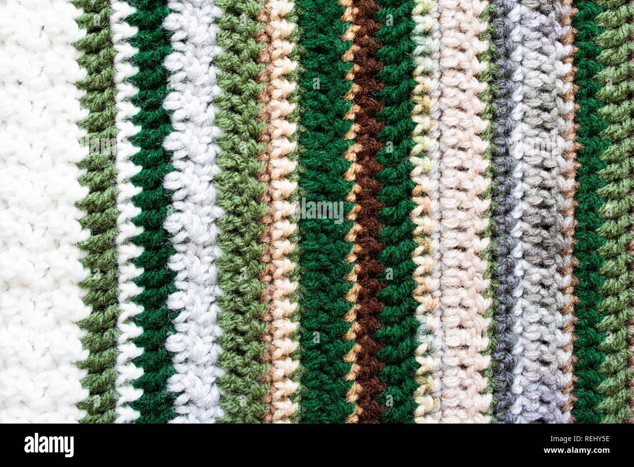 Closeup of an afghan crocheted from acrylic yarn with colors of the changing seasons, from winter into spring. Stock Photo
