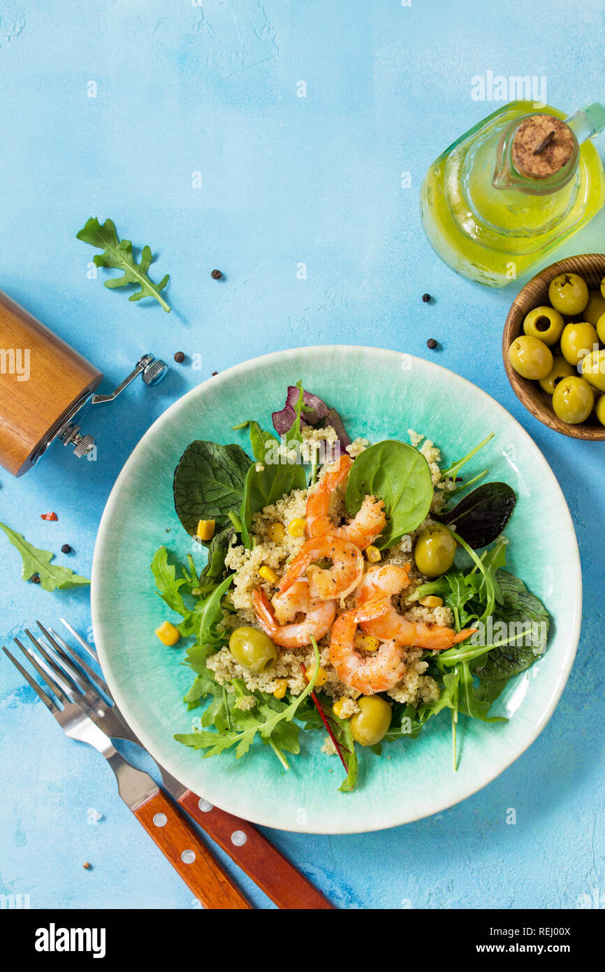 Diet menu, Vegan food. Healthy salad with quinoa, arugula, Shrimps and olives on a blue stone table. Top view flat lay background. Copy space. Stock Photo