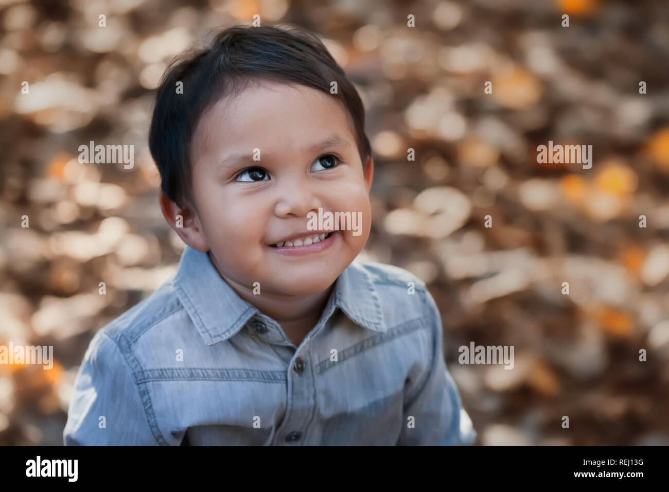 A smiling hispanic boy looking up, gazing into the sky with an expression of hope or day dreaming positive thoughts. Stock Photo