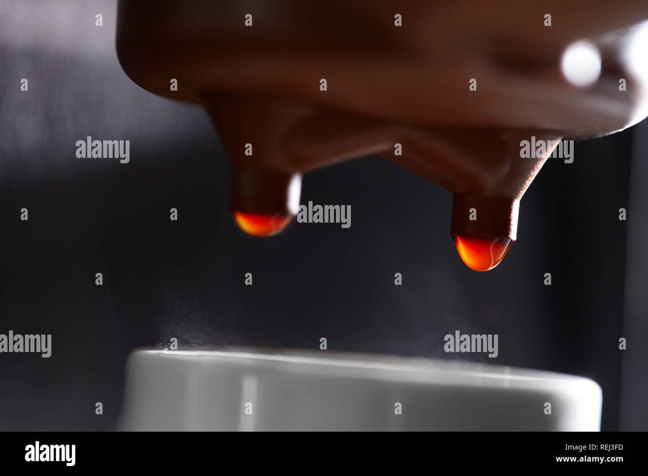 Macro photo of dripping coffee in a coffee machine dripping into a cup