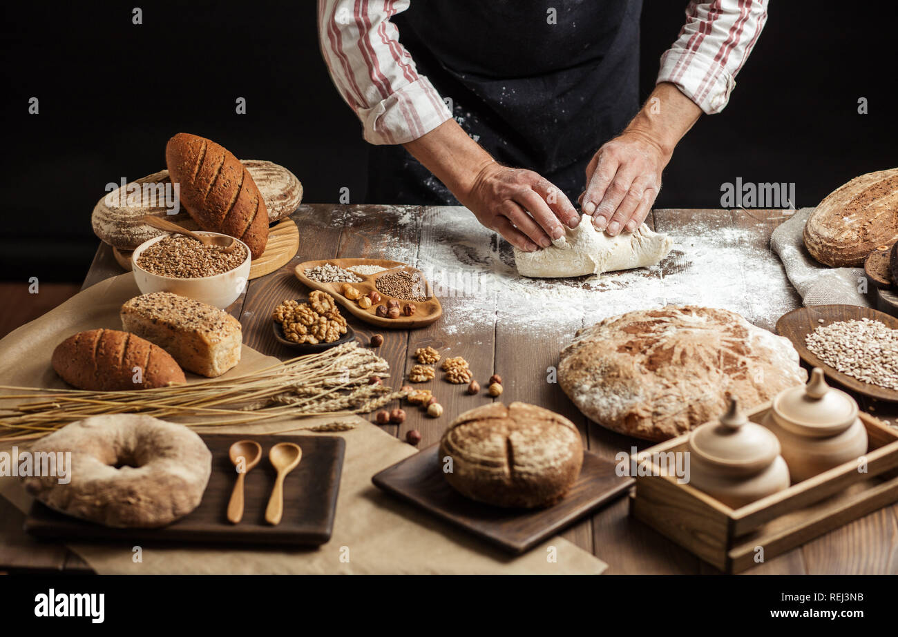 Close up of baker hands kneading dough and making bread with a rolling pin. Stock Photo