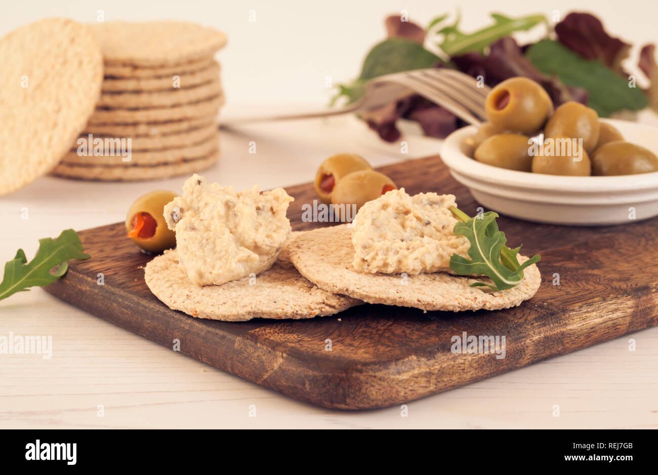 Gluten free oatcakes with hummus and green olives and salad on wooden board Stock Photo