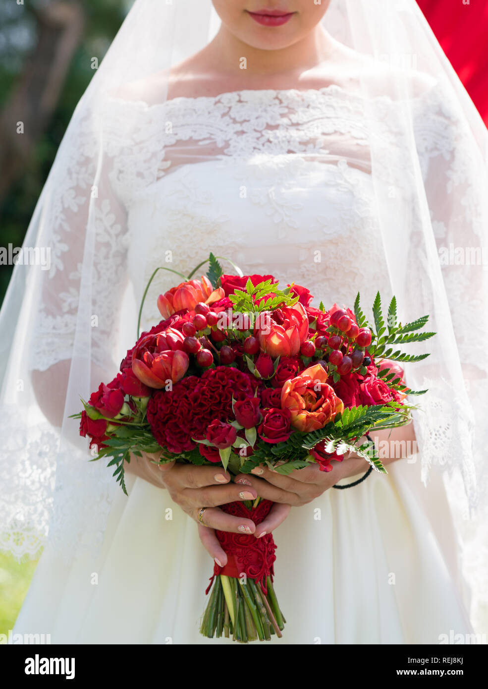 bride holds a bright red wedding bouquet Stock Photo