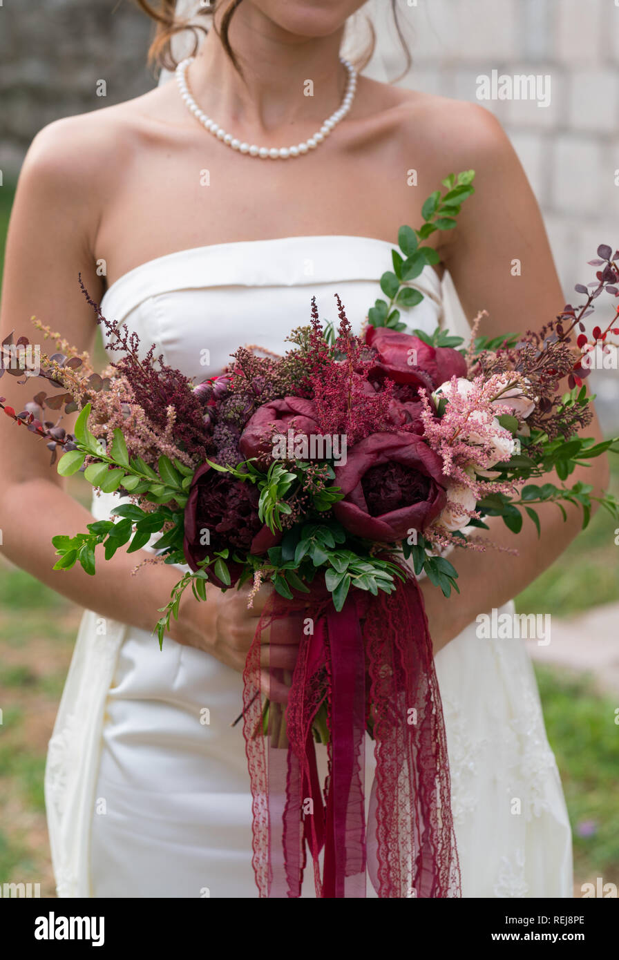 the bride holds a dark red wedding bouquet in her hands Stock Photo