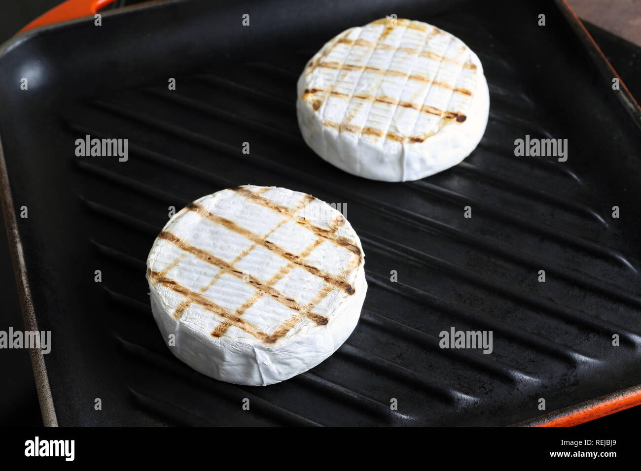 Tasty chequered camembert cheese frying on cast iron grill pan ...
