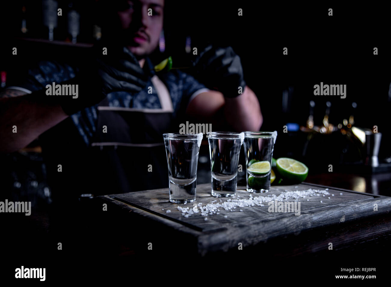 aperitif with friends in the bar, three glasses of alcohol with lime and salt for decoration. Tequila shots, selective focus. Stock Photo