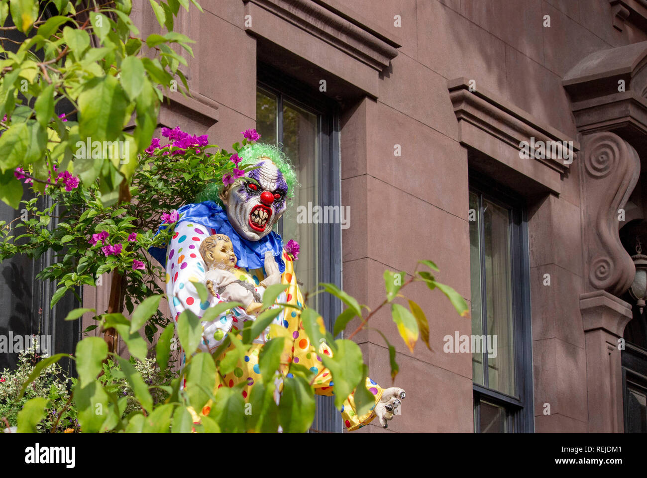 A scary clown mannequin on a staircase outside a house in New York City to celebrate Halloween Stock Photo