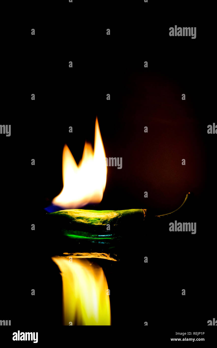 On fire green pepper burning in front of dark background Stock Photo Alamy