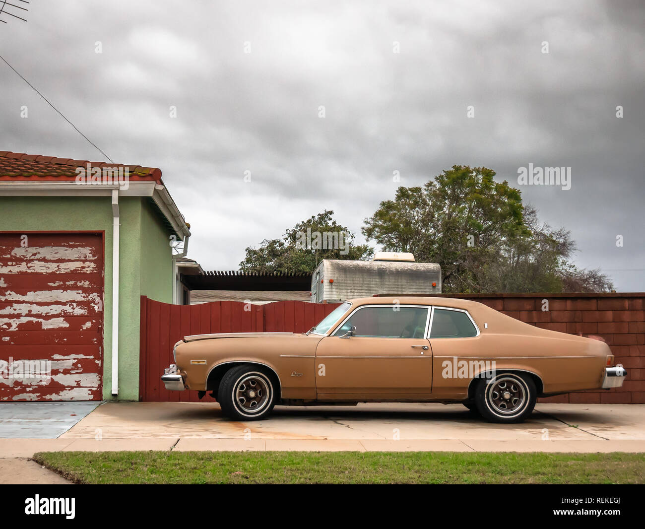 A classic steel car parked in front of deep red fence Stock Photo - Alamy