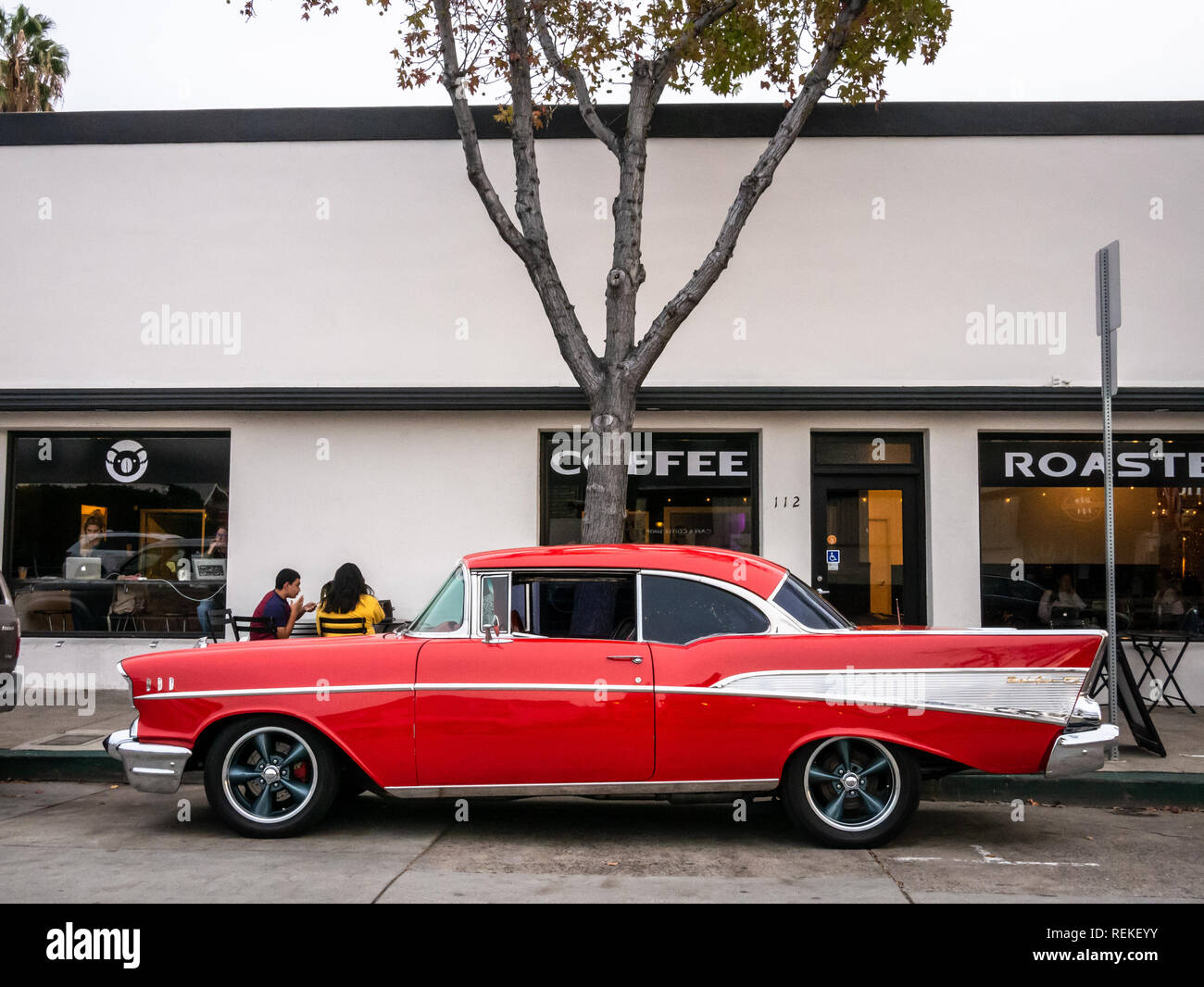 A classic red Chevy Bel Air parked in front of a coffee shop downtown. Stock Photo