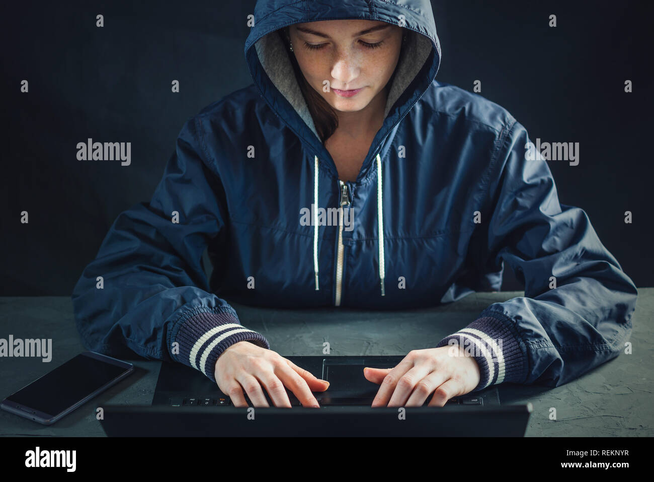 Hacker teen programmer uses a laptop to hack the system. Stealing personal data. Creation and infection of malicious virus. The concept of cyber crime Stock Photo