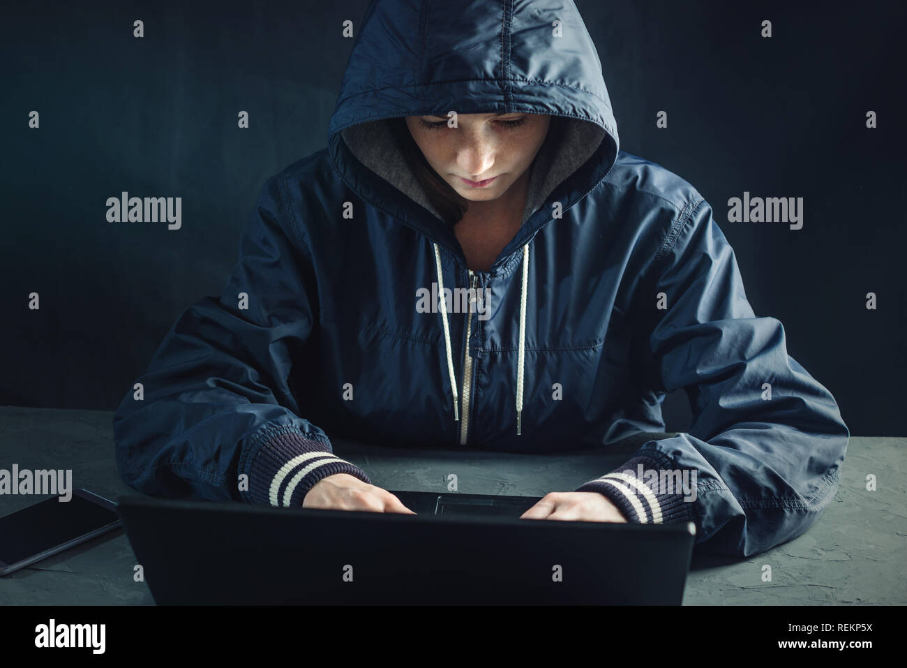 Hacker teen programmer uses a laptop to hack the system. Stealing personal data. Creation and infection of malicious virus. The concept of cyber crime Stock Photo