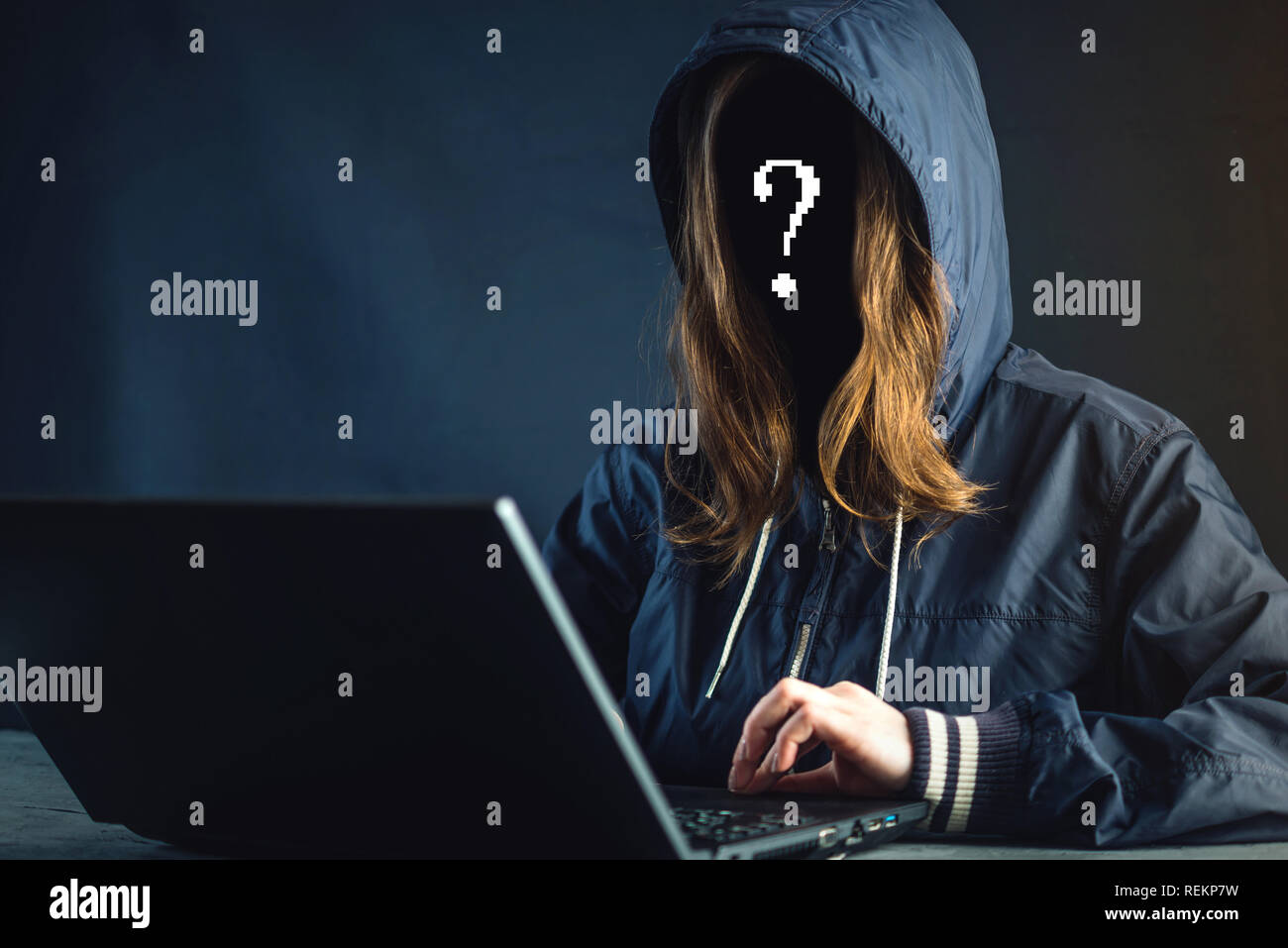 Anonymous girl hacker programmer uses a laptop to hack the system. Stealing personal data. Creation and infection of malicious virus. The concept of c Stock Photo
