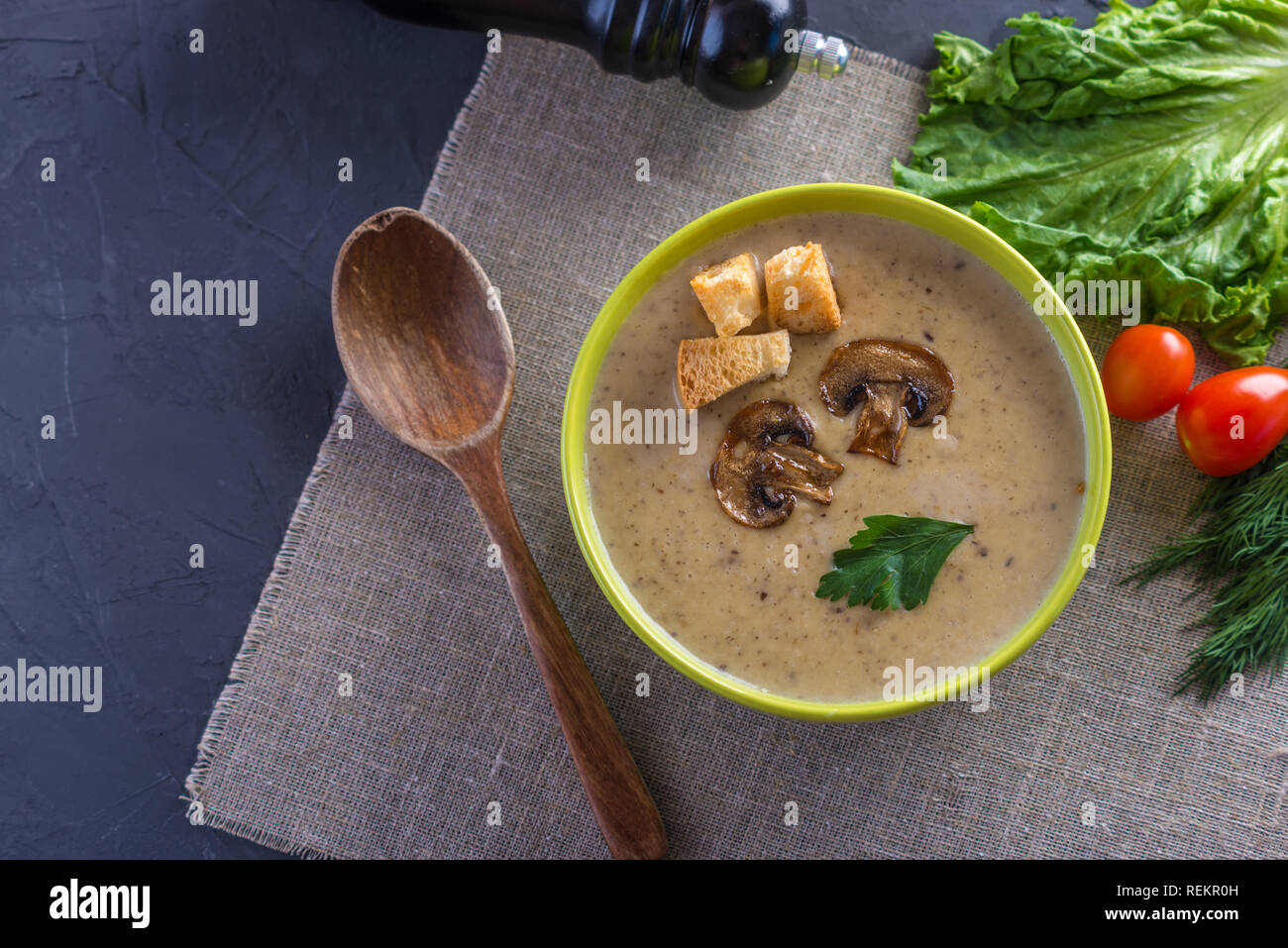 Cream of mushroom soup in a green bowl on the table. Dark background