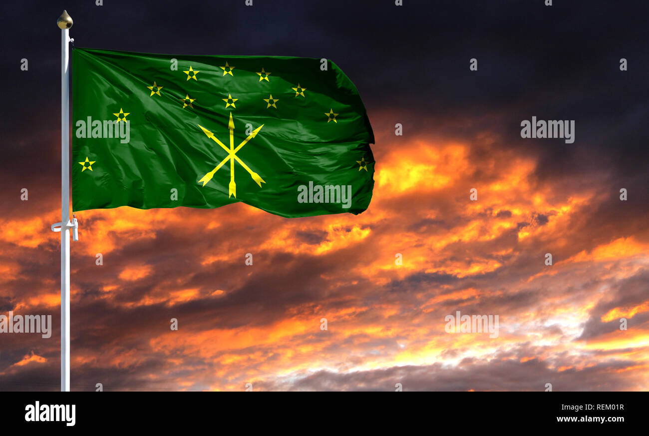 flag of Adygea on flagpole fluttering in the wind against a colorful sunset sky. Stock Photo