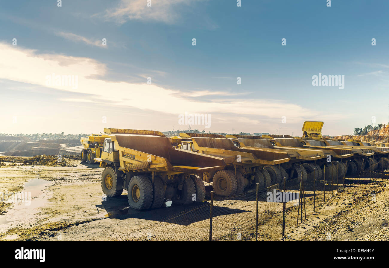 Large dumper trucks in the open pit mine of Riotinto, lined up waiting for their next assignment with blue sky in the background Stock Photo