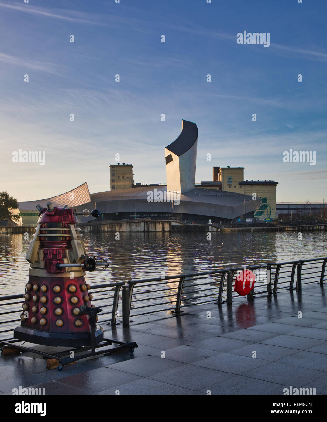 Dalek on display by the Manchester Ship Canal with Imperial War Museum North in the background, MediaCityUK, Salford Quays, Greater Manchester, U.K. Stock Photo