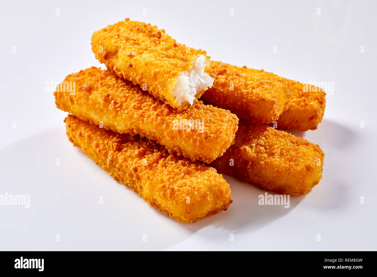 Tasty crispy deep fried fish fingers lying against white background