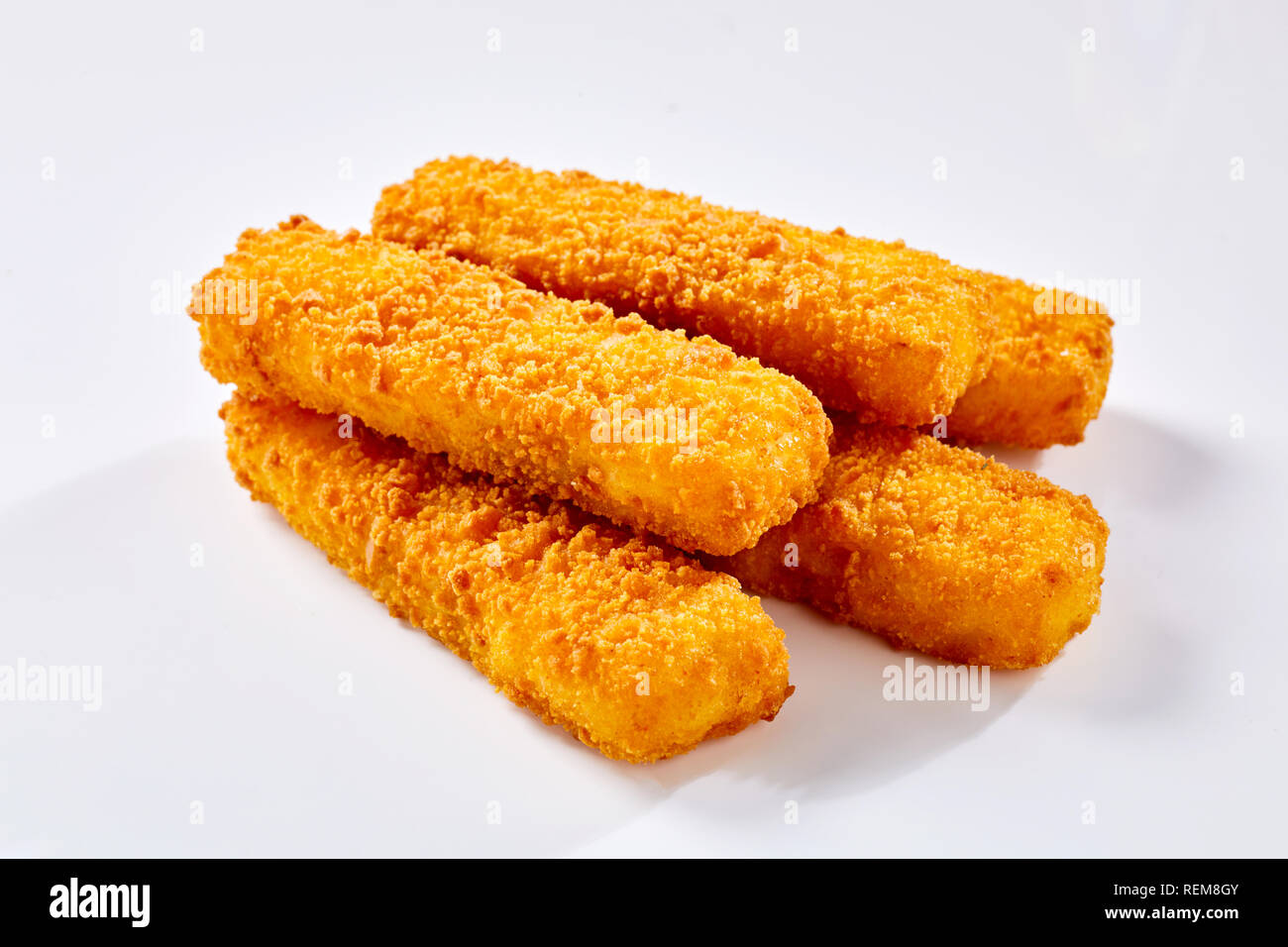 Tasty crispy deep fried fish fingers lying against white background