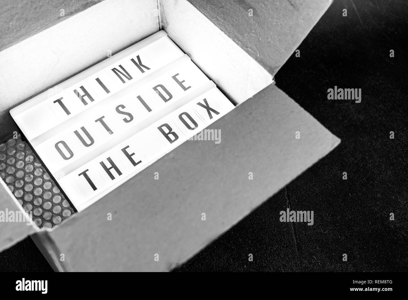 Think outside the box message on lightbox coming out of a parcel ...