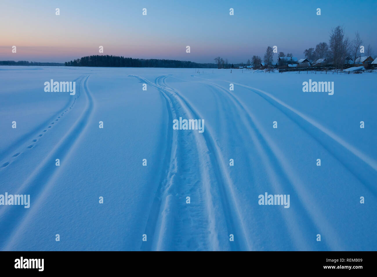 Winter dawn and snowmobile traces on the snow on frozen Peno lake, Tver oblast, Russia Stock Photo