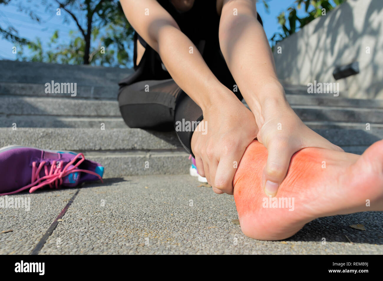 Young woman massaging her painful foot from exercising and running Sport and excercise concept. suffering from an ankle injury while exercising and ru Stock Photo